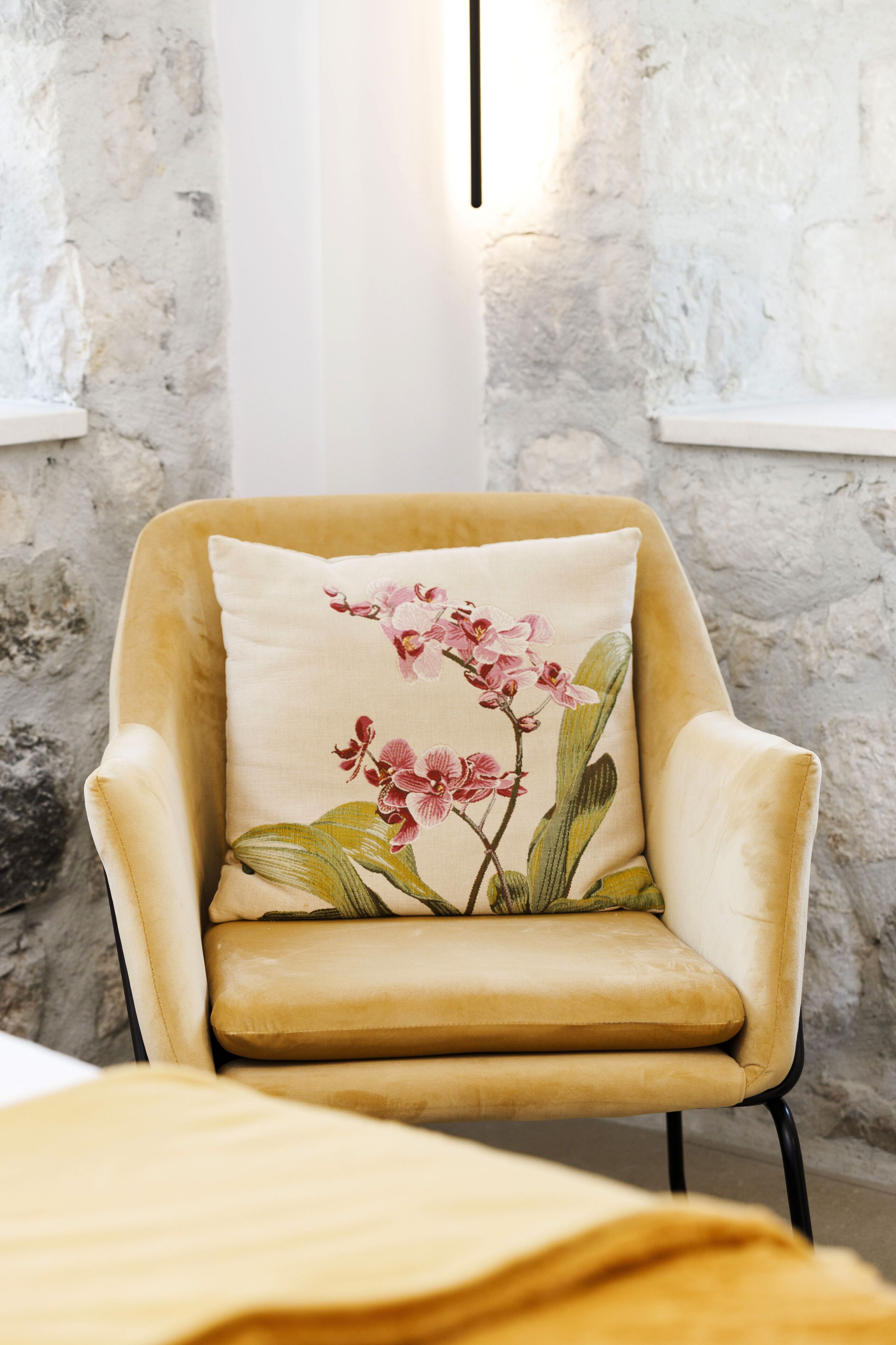 Une chaise avec un coussin à motifs floraux, placée contre un mur à texture.