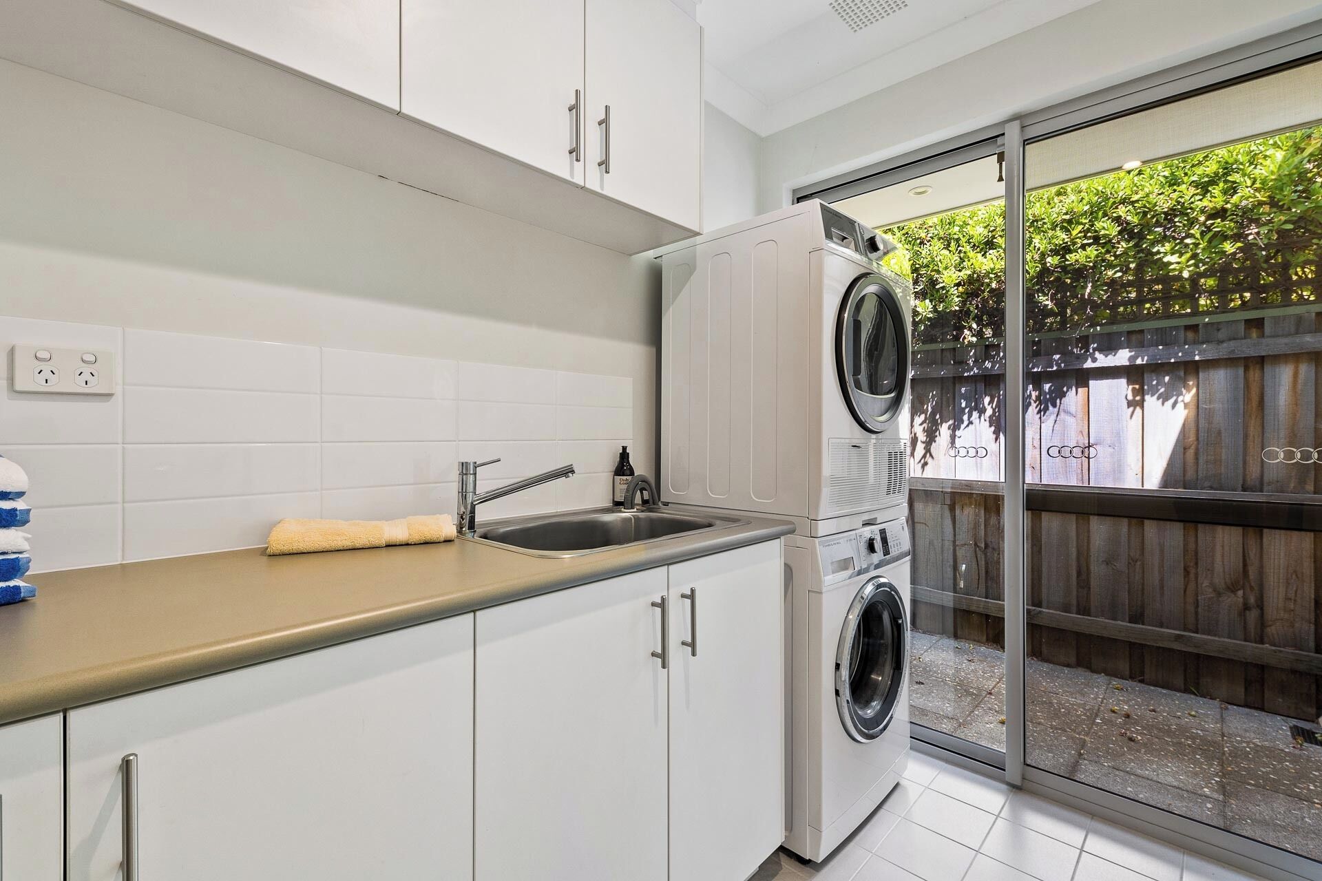 A compact kitchen with white cabinets, a stainless steel sink, and a built-in washer and dryer.
