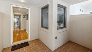 Un couloir avec un plancher en bois, une porte donnant sur une autre pièce et une fenêtre avec vue sur un lit.