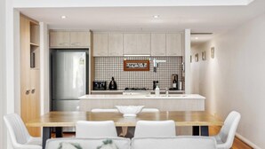 Une cuisine moderne dotée d’un îlot central, de meubles blancs et d’un dosseret carrelé.