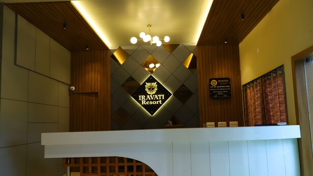 Un mostrador de recepción en Iravati Resort con un diseño moderno, un cartel y un panel de pared de madera.