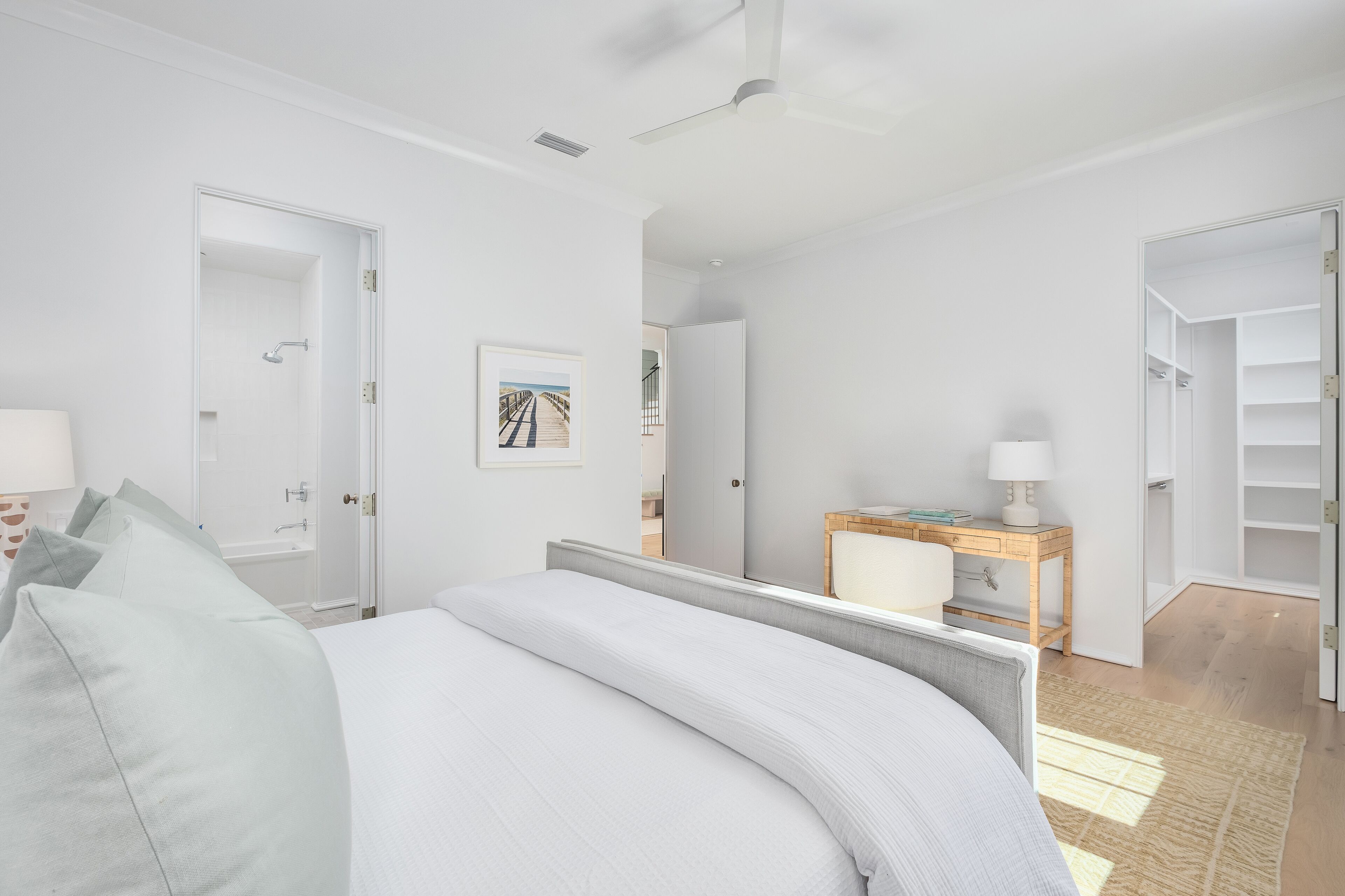 Ein modernes Hotelzimmer mit einem großen Bett, einem Nachttisch aus Holz, einem Schreibtisch und einem begehbaren Kleiderschrank.