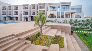 A modern hotel with multiple balconies, a swimming pool, and a well-maintained garden area. - Al Masa Hotel El Sokhna (Ataqah)