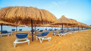 A beach with rows of blue lounge chairs and thatched umbrellas. - Al Masa Hotel El Sokhna (Ataqah)