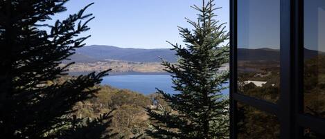 A view through a window of a lake, surrounded by trees and distant hills.