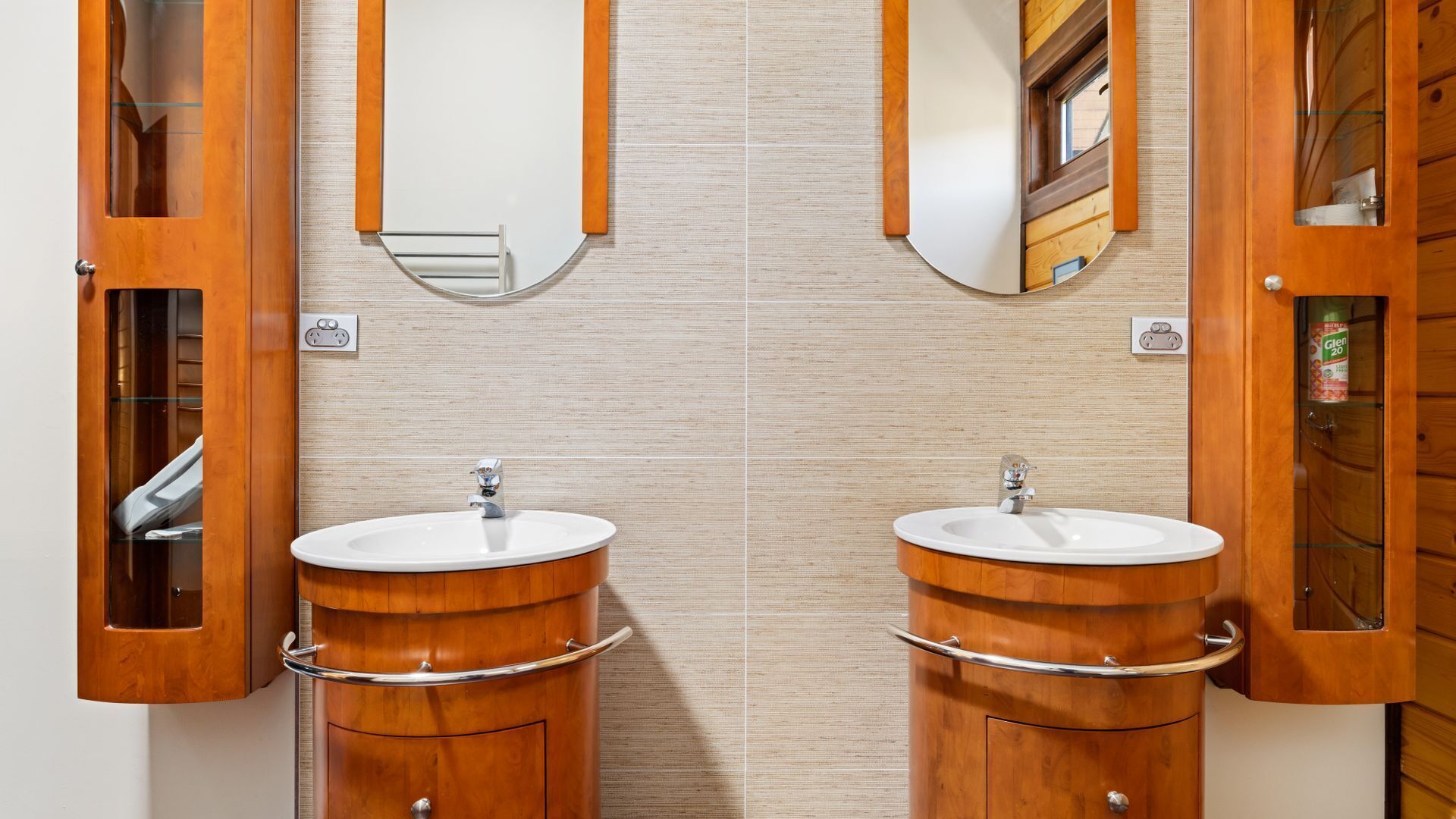 A bathroom with two wooden vanity sinks, each with a mirror above.