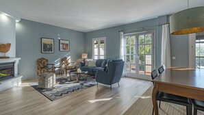 A spacious living room with a fireplace, a blue sofa, and a dining table. - Stunning three bedroom town house walking distance to Puente Romano Hotel (Marbella)