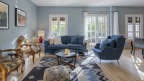 A living room with a blue sofa, two armchairs, a coffee table, and a patterned rug. - Stunning three bedroom town house walking distance to Puente Romano Hotel (Marbella)