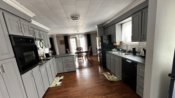 A spacious kitchen with grey cabinets, a black refrigerator, and a wooden floor. - Quiet Country style living, your home away from home.  (Stephenville)