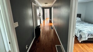A narrow hallway with wooden flooring leading to a bedroom with a bed. - Quiet Country style living, your home away from home.  (Stephenville)