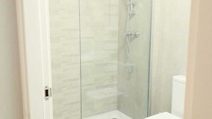 A modern bathroom with a glass-enclosed shower, a white toilet, and a tiled floor. - Apartamento Pamplona (Pamplona)