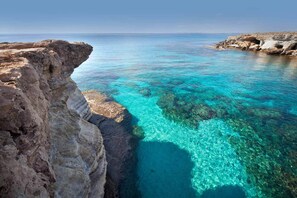 Un paisaje costero con aguas turquesas cristalinas y acantilados rocosos.