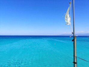 Vista despejada del océano, con el mástil y la aparejo de un barco en primer plano.