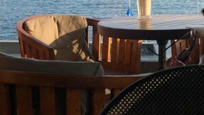 Una mesa de madera con una bebida, una silla y vistas al mar.