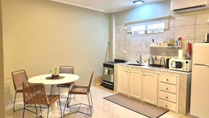 A compact kitchen with a dining area, featuring a round table, two chairs, a stove, a microwave, and a refrigerator. - En Micro Centro, Luminoso, Ubicación Ideal (Puerto Iguazú)