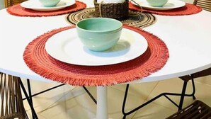 A round dining table with white plates and teal bowls, surrounded by red placemats. - En Micro Centro, Luminoso, Ubicación Ideal (Puerto Iguazú)