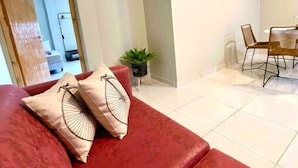 A living room with a red sofa, a dining area with a table and chairs, and a hallway leading to a bathroom. - En Micro Centro, Luminoso, Ubicación Ideal (Puerto Iguazú)