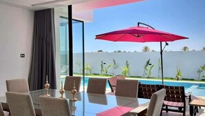Un comedor moderno con una mesa de vidrio, seis sillas y un paraguas rojo.