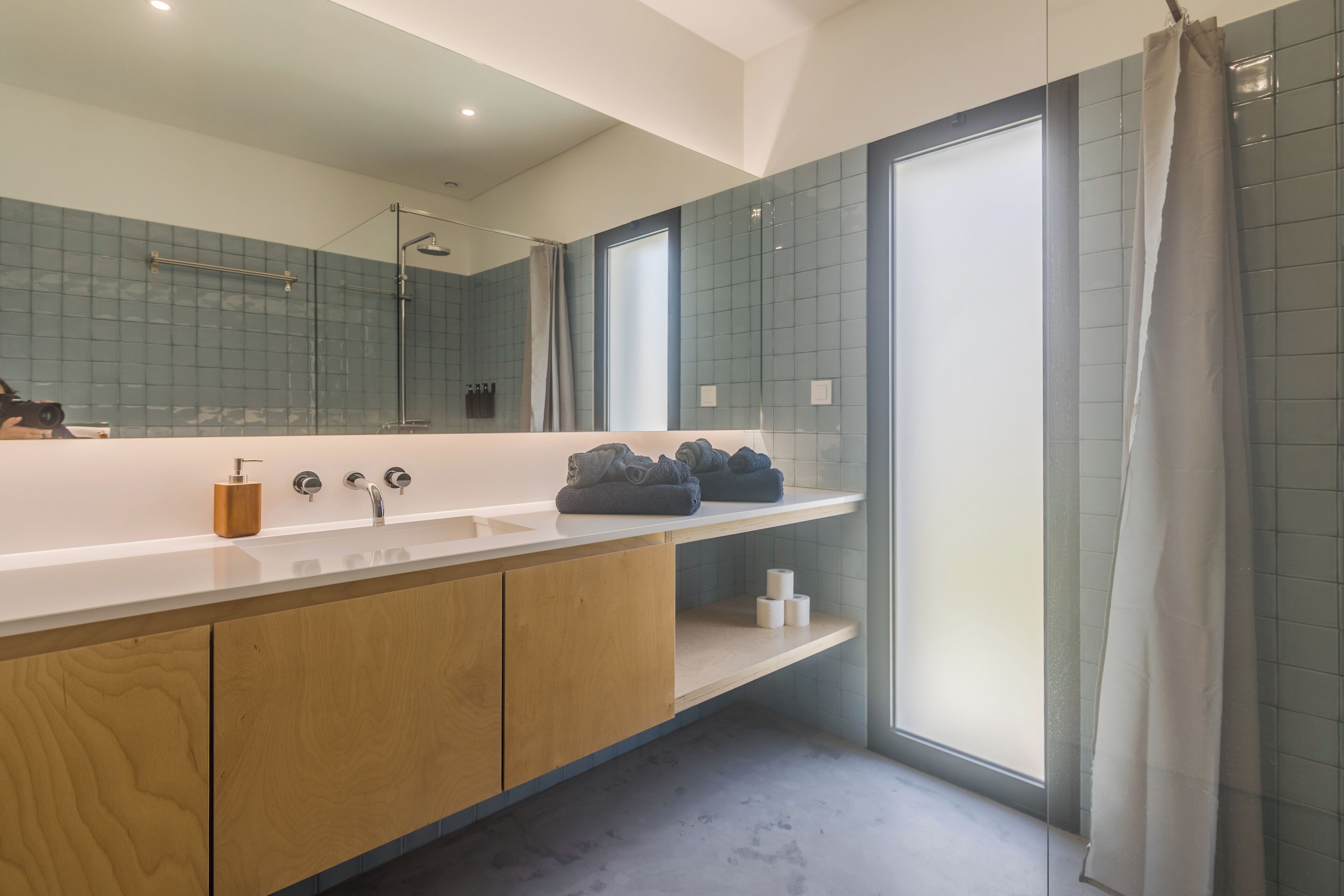 A modern bathroom with a large mirror, a sink, and a shower area.