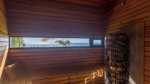 Ein Holzhütten-Inneres mit einem großen Fenster, das Blick auf den Ozean gewährt.