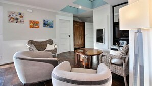 Una sala de estar con un sofá, sillones, una mesa redonda y obras de arte en las paredes.