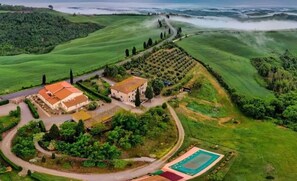 Surrounded by lush greenery and rolling hills, this property offers a serene setting with a tennis court and a charming building.
