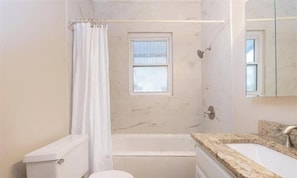 A bathroom with a bathtub, toilet, and sink.