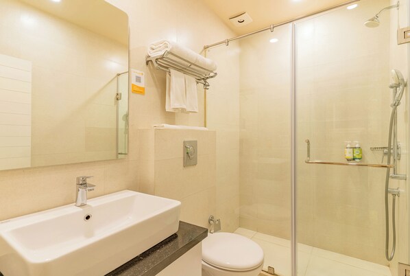 A modern bathroom with a large sink, toilet, and glass-enclosed shower area.