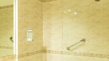 Une salle de bain avec une douche à parois de verre, une baignoire blanche et un meuble-lavabo surmonté d’une pile d’serviettes.