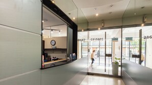 A modern hotel lobby with a glass entrance, a clock, and a visible number 286. - Le Batiment Apartments (Buenos Aires)