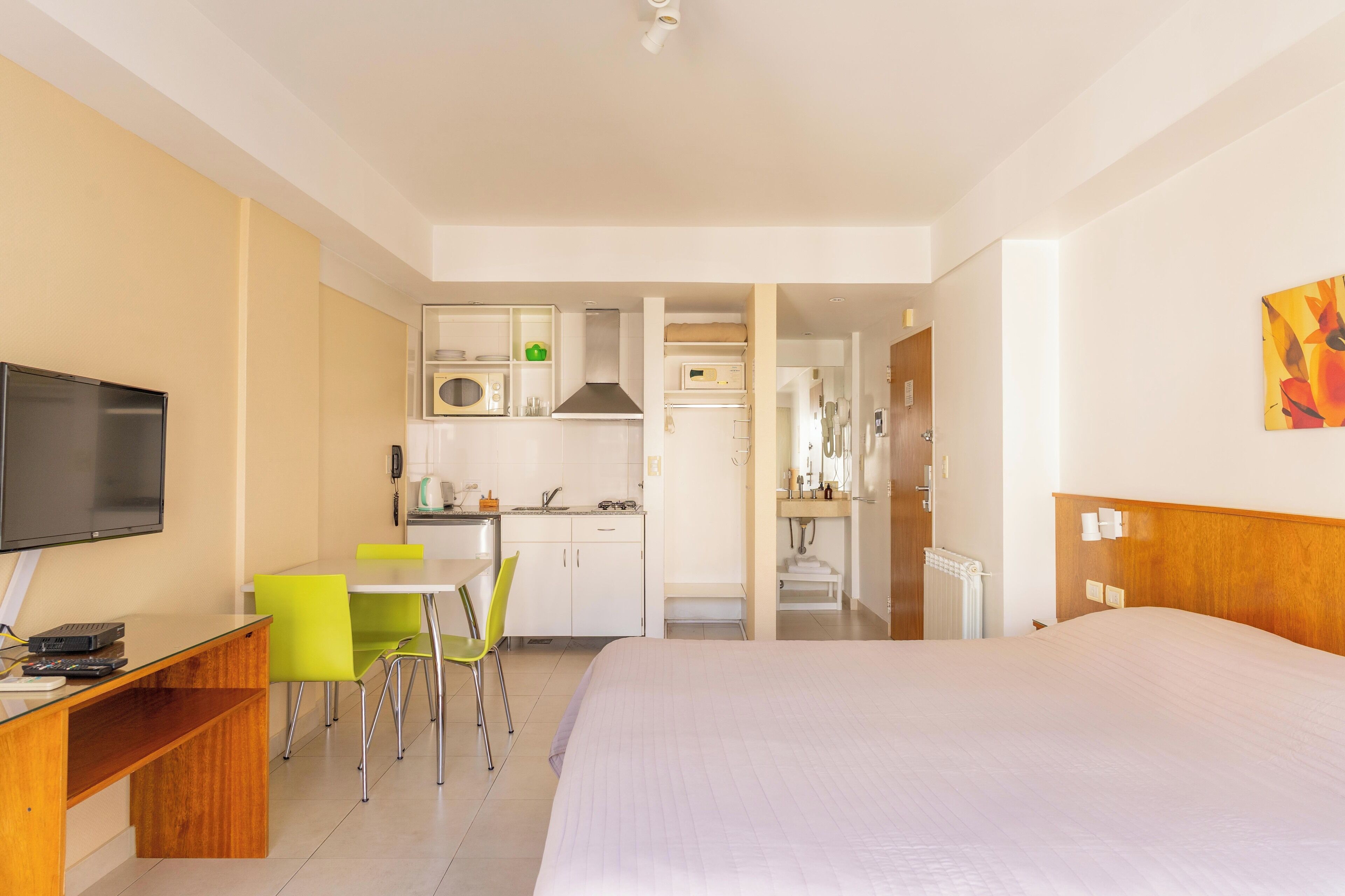 Una camera d'hotel con un letto, una scrivania con televisore, angolo cottura e bagno.