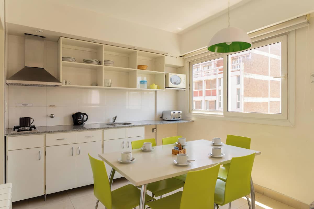Cocina moderna con armarios blancos, estufa integrada y ventana con vistas a edificios.