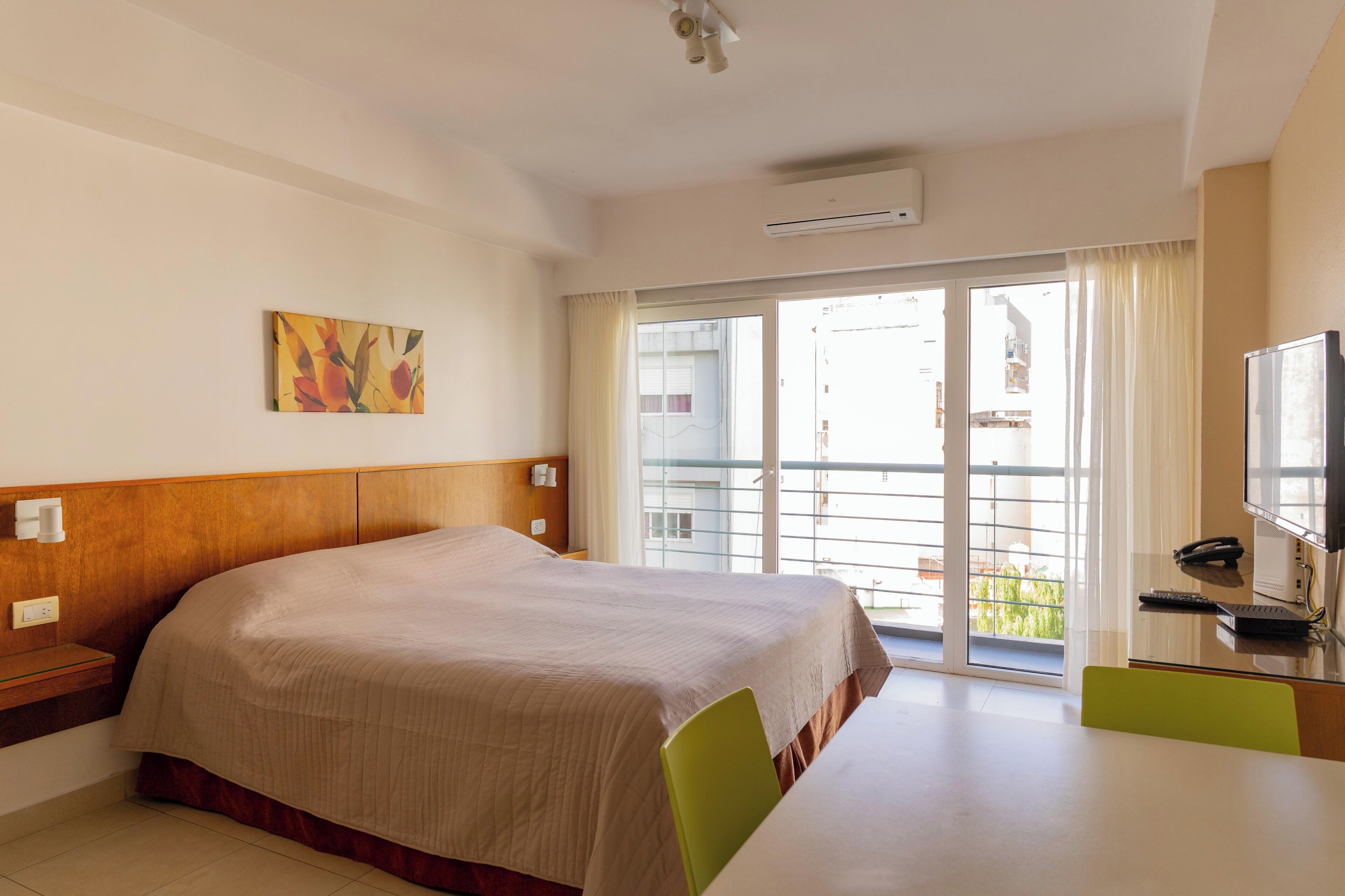 A hotel room with a bed, a desk with a chair, a television, and a window with curtains.