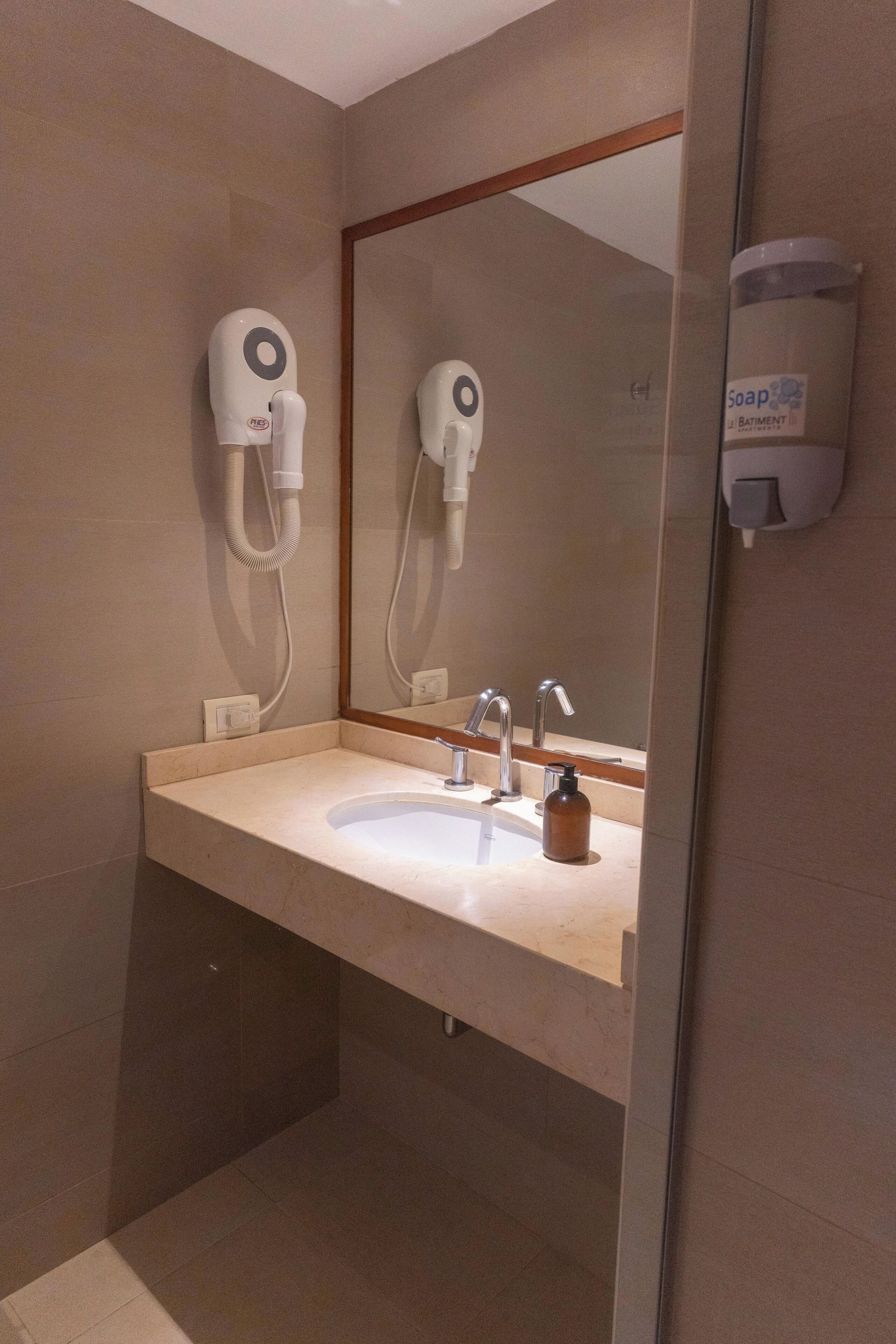 A bathroom with a sink, mirror, and hand dryer.
