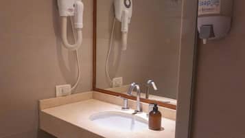 A bathroom with a sink, mirror, and hand dryer.
