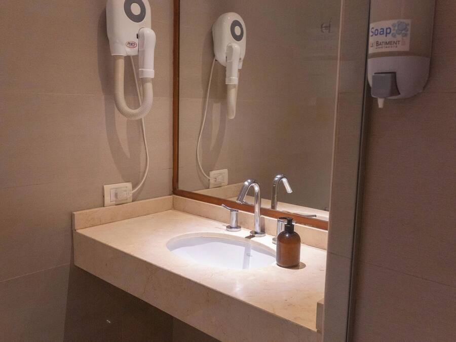 A bathroom with a sink, mirror, and hand dryer.