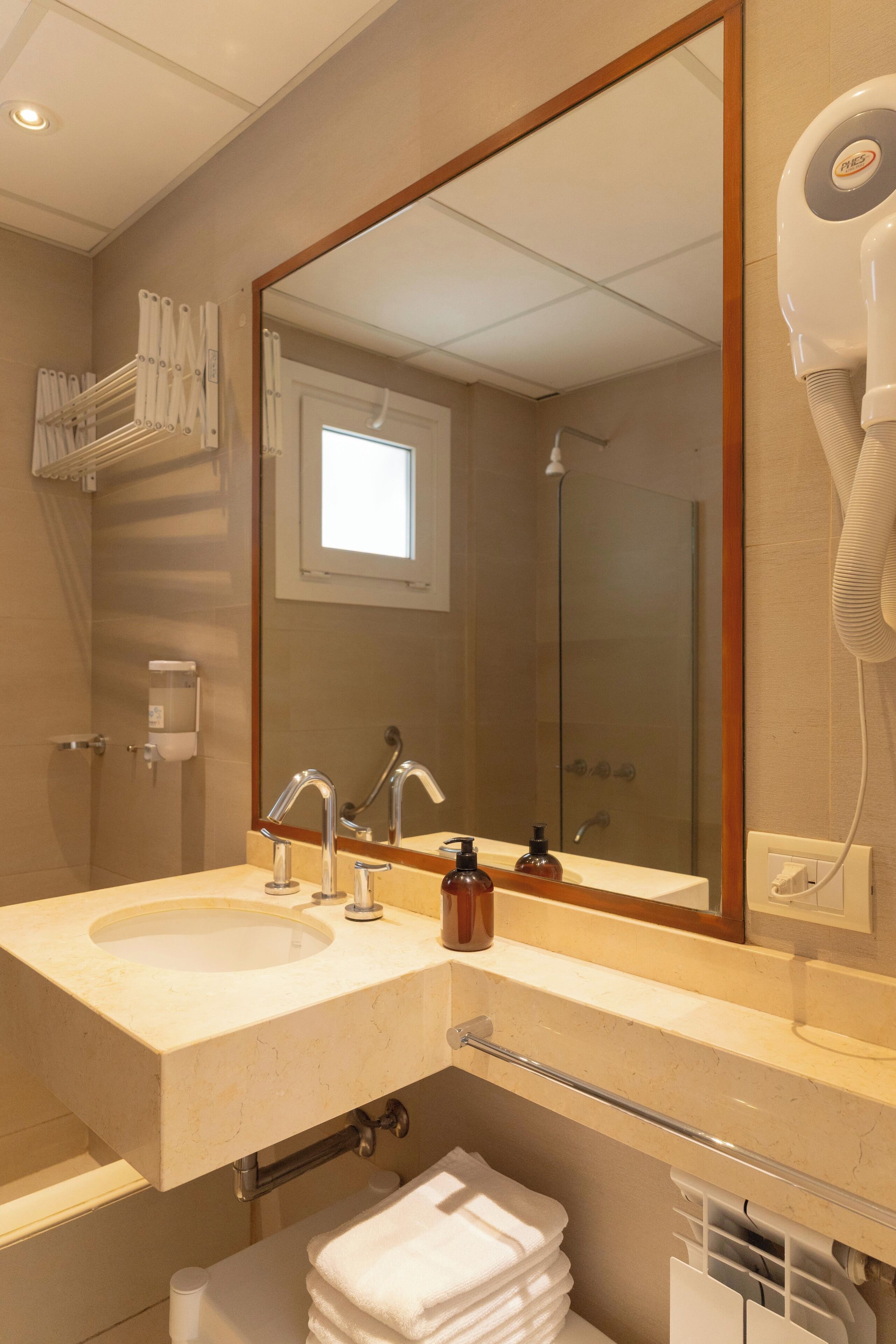 Une salle de bain avec deux lavabos, un grand miroir, un sèche-cheveux et un porte-serviettes.