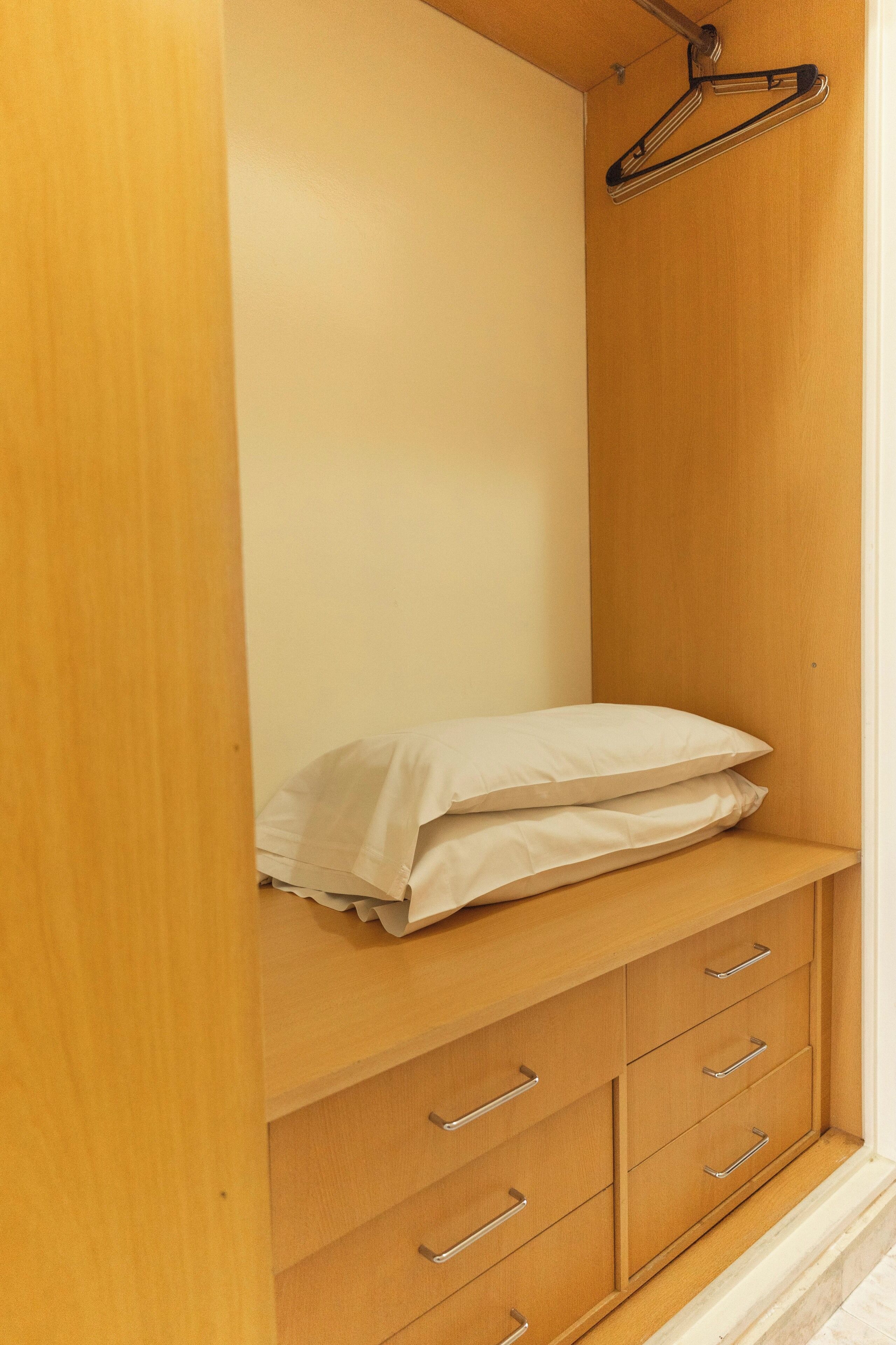 A wooden wardrobe with multiple drawers and a hanging space.