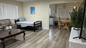 A living room with a sofa, a coffee table, a bed, and a dining area with a table and chairs.