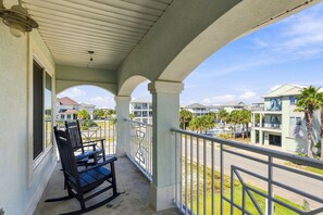 A balcony with a view of other buildings, a chair, and a railing. - ☀️Sea Forever-Walk2Beach-Stunning Home-5BR-Great Location☀️ (Pensacola Beach)