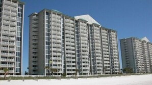 Un hôtel situé en bord de mer, composé de plusieurs immeubles de grande hauteur, doté de balcons et donnant sur une plage de sable.