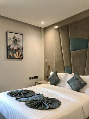 A modern hotel room with a large bed, decorative pillows, a wall-mounted artwork, and a bedside table with a lamp. - East Garden Plus Serviced apartments شقق حديقة الشرق بلس للشقق المخدومة  (Al Khobar)