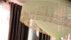 A bed with white linens and a red accent, a canopy with lace detailing, and dark curtains. - Zeyman's Apartments (Kigali)