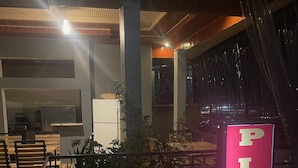 A restaurant interior with a prominent 'PIZZA' sign, seating area, and a counter with a cash register. - Zeyman's Apartments (Kigali)