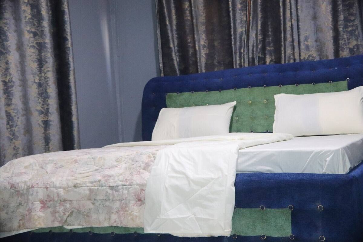 Un lit avec une tête de lit bleue, une literie blanche et une couverture à motifs floraux.