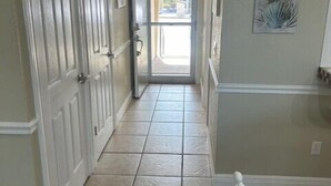 A hallway with white doors, a tiled floor, and two wall-mounted artworks. - Direct Oceanview Premium Flat with 2 Bed/2 Bath +Murphy Bed. Just Renovated! (St. Augustine)