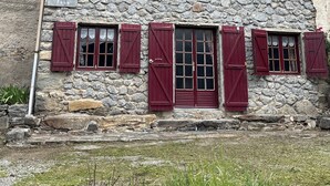 Ein Steinhaus mit roten Fensterläden und einem Ziegeldach.