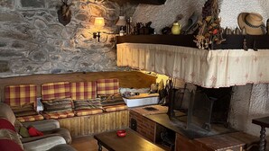 Ein gemütliches Wohnzimmer mit Steinwand, Kamin, einer Couch und einem Couchtisch.