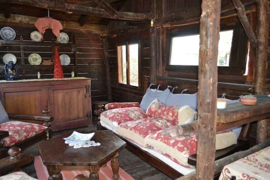Ein rustikales Blockhaus-Interieur mit einer Holzdirektbank, einem Holztisch und einem Schrank mit dekorativen Tellern.