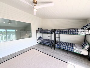A bunk bed room with a large window, a ceiling fan, and a view of the outdoors. - Royal Palms: Your Island Retreat in Near Tahiti Beach (Hope Town)
